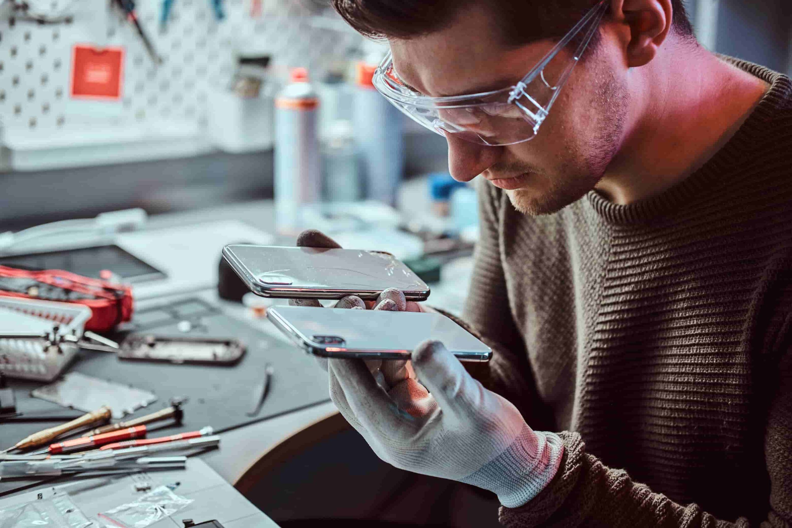 electronic technician holds two identical smartphones comparison one hand broken another new 1 scaled